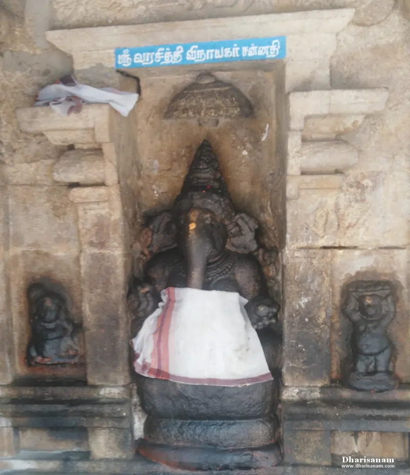 Black stone Vinayakar idol in a carved niche under a blue Tamil name board