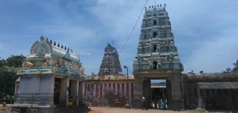 A tall tower with a gate, a smaller tower behind it, and a small domed shrine on the left