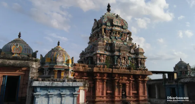 A tall sculpted tower above a red stone wall, with smaller domed shrines beside it.