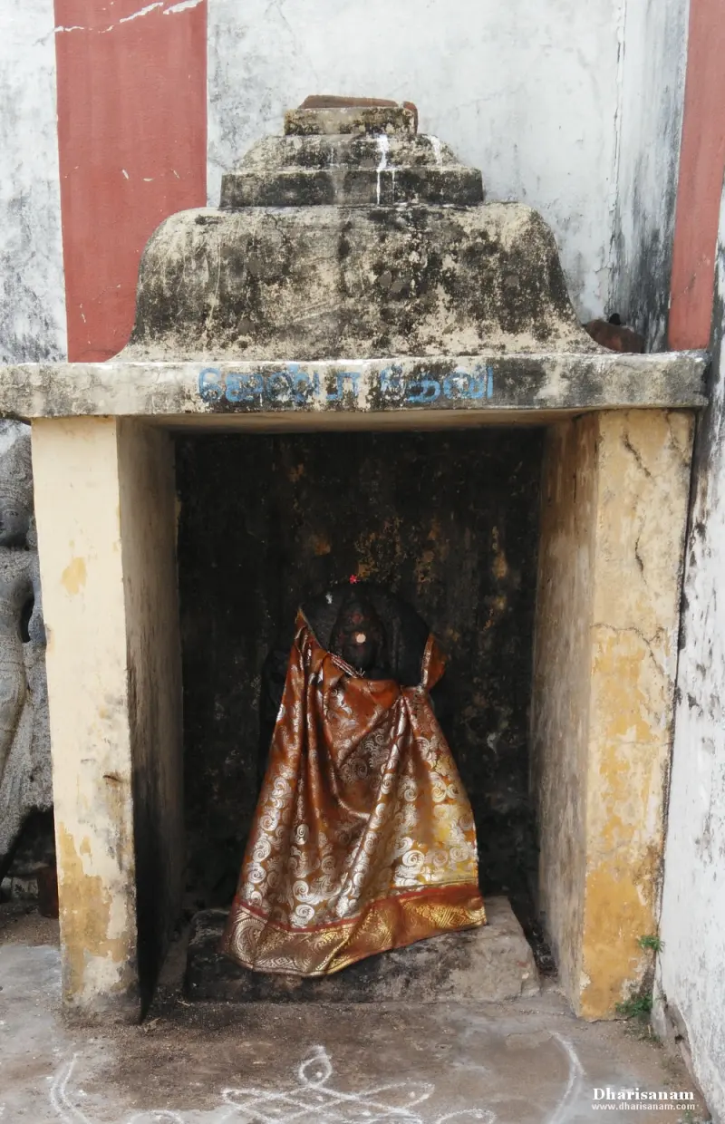 A small open shrine with a stone roof, holding an idol covered in an orange brocade cloth.