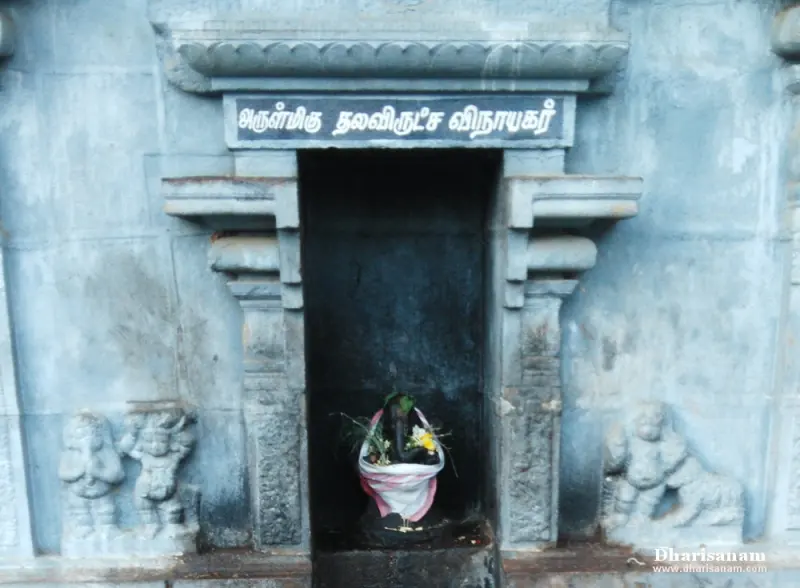 A small niche with a name board above holds a Vinayakar idol wrapped in cloth, with relief carvings at each side