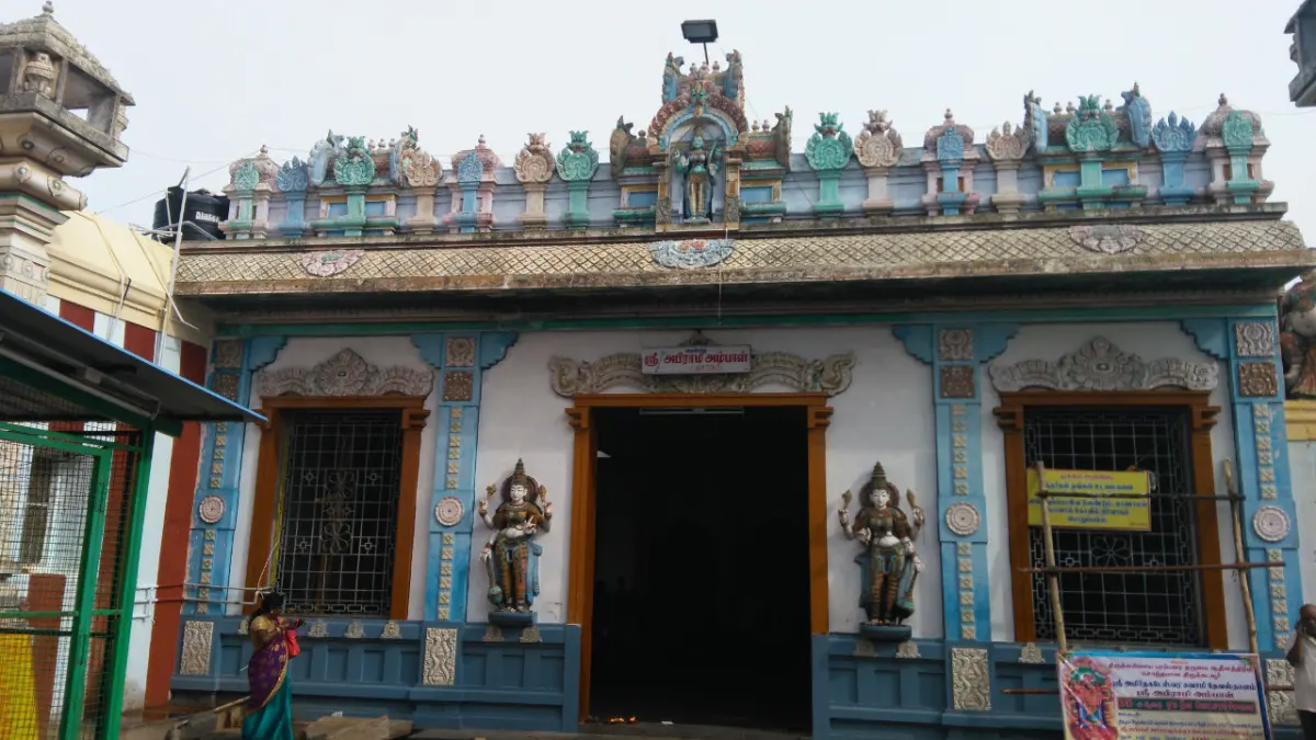 Blue and white shrine front with a dark doorway, two guardian statues beside it and a painted roof of figures.