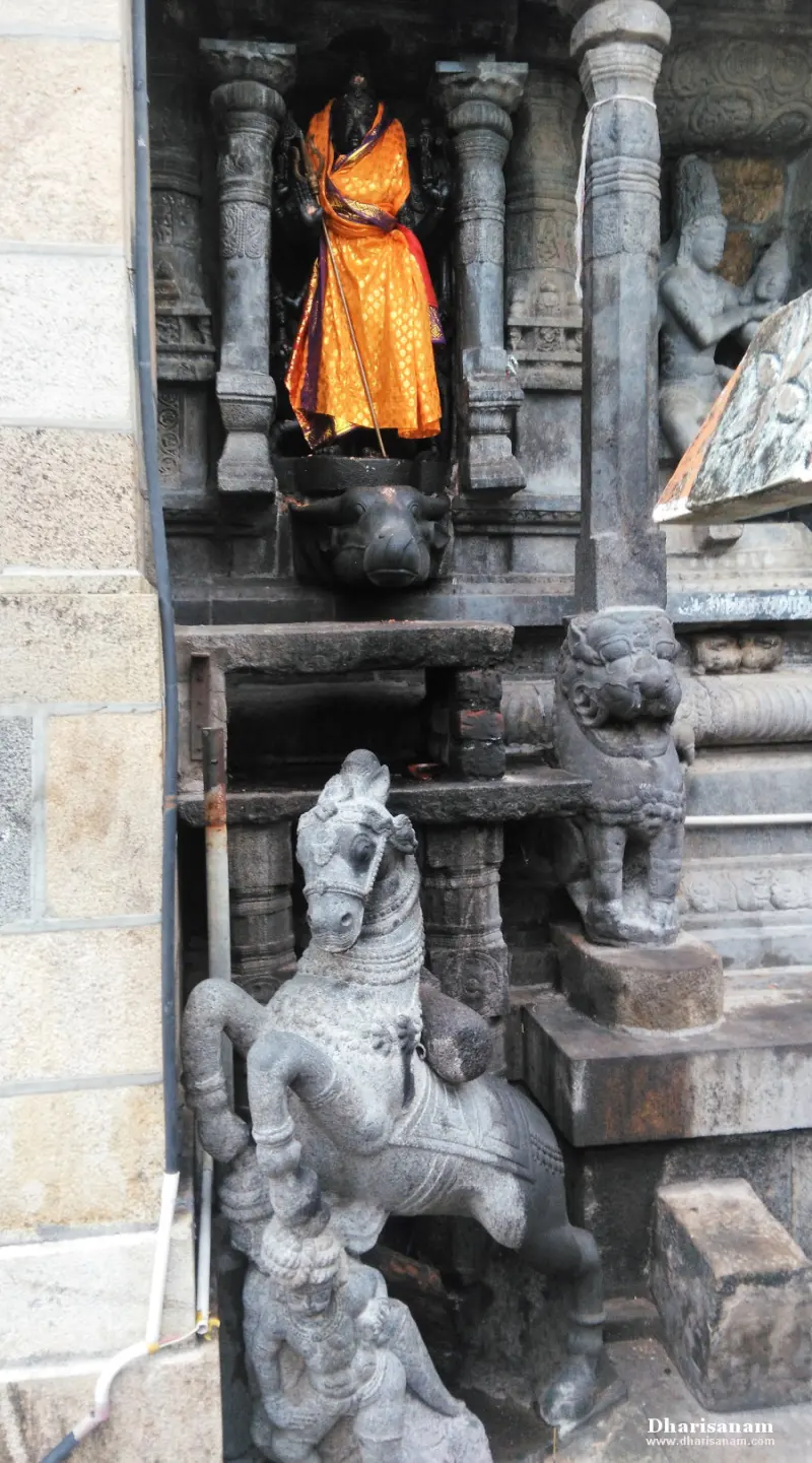 An idol in orange cloth above a bull in a pillared niche, with a rearing stone horse in front.