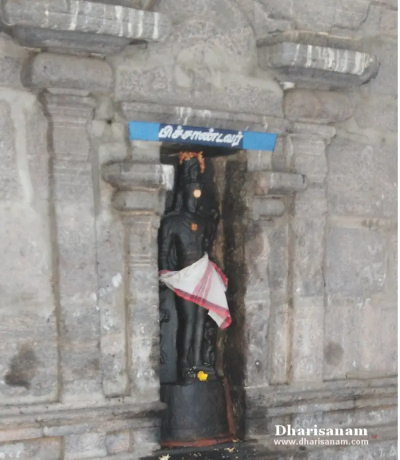 Standing black stone idol in a wall niche under a blue Tamil name board