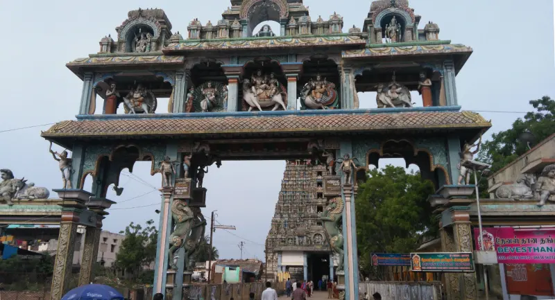 A painted entrance arch with sculpted figures; the temple tower is seen through it.