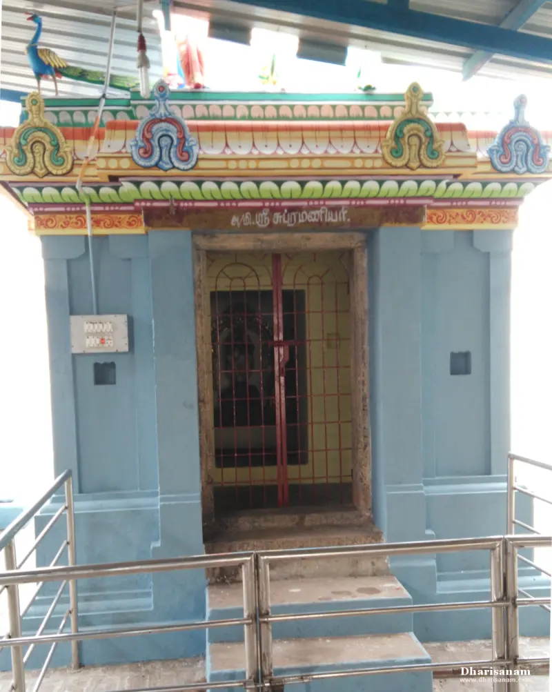 A small blue shrine with a Tamil name board, a barred door and a peacock figure on the roof