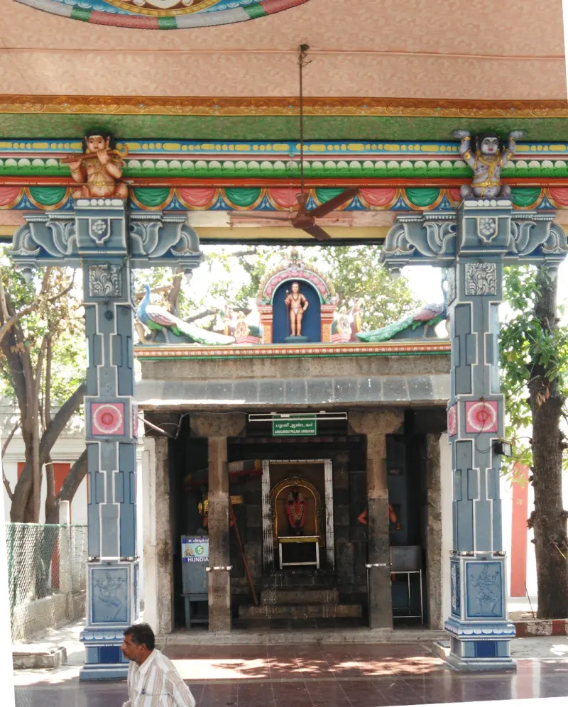Two painted pillars frame a small shrine with a lit doorway and a painted tower above it.