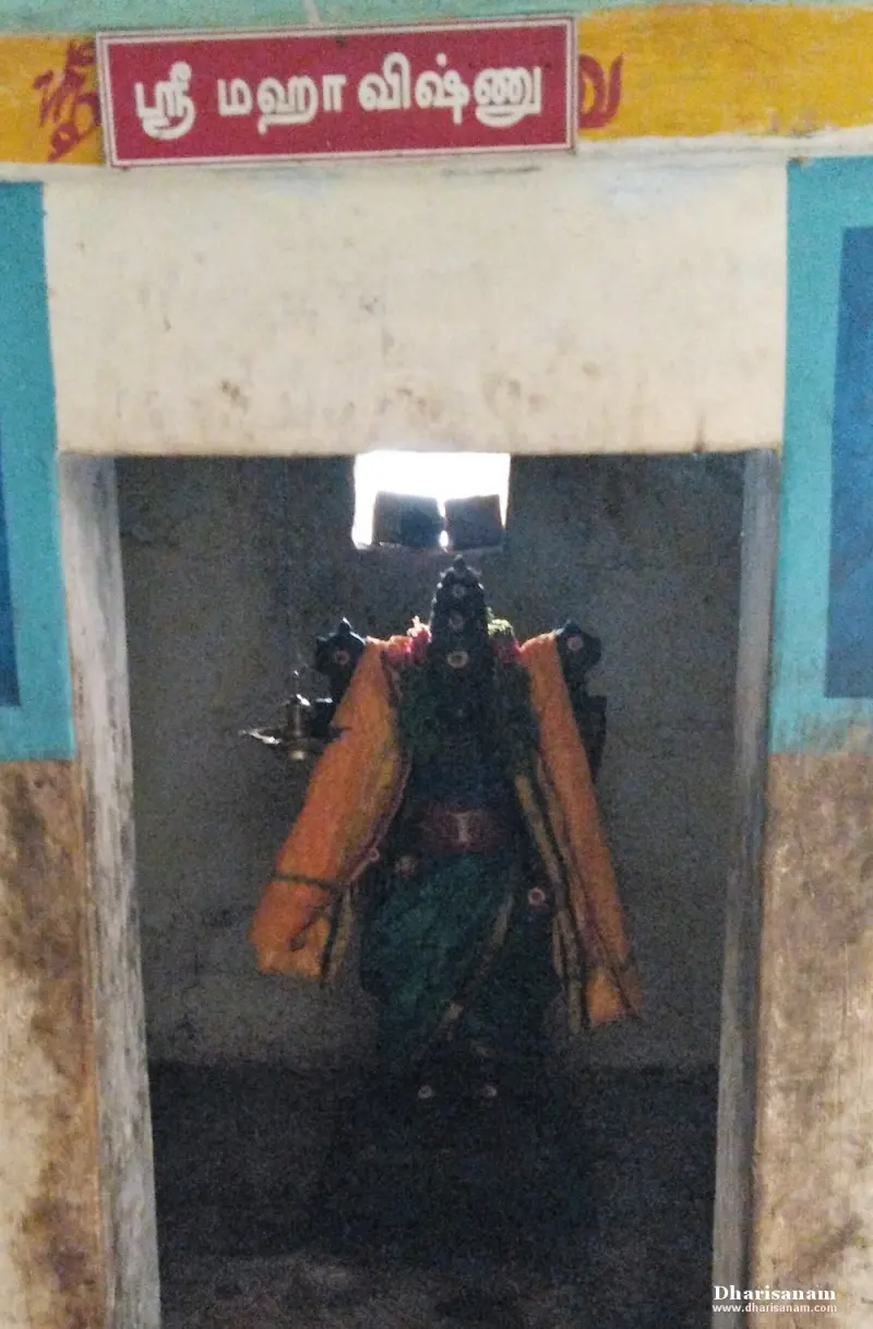 A small shrine with a standing idol in an orange cloth, and a board above reading Sri Mahavishnu in Tamil