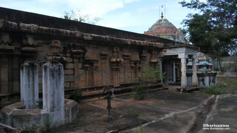A carved stone wall with pilasters, a domed painted tower rising behind it, and two stone posts in front