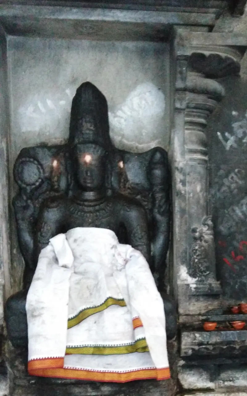 Seated dark stone figure in a niche with a white cloth across its lap