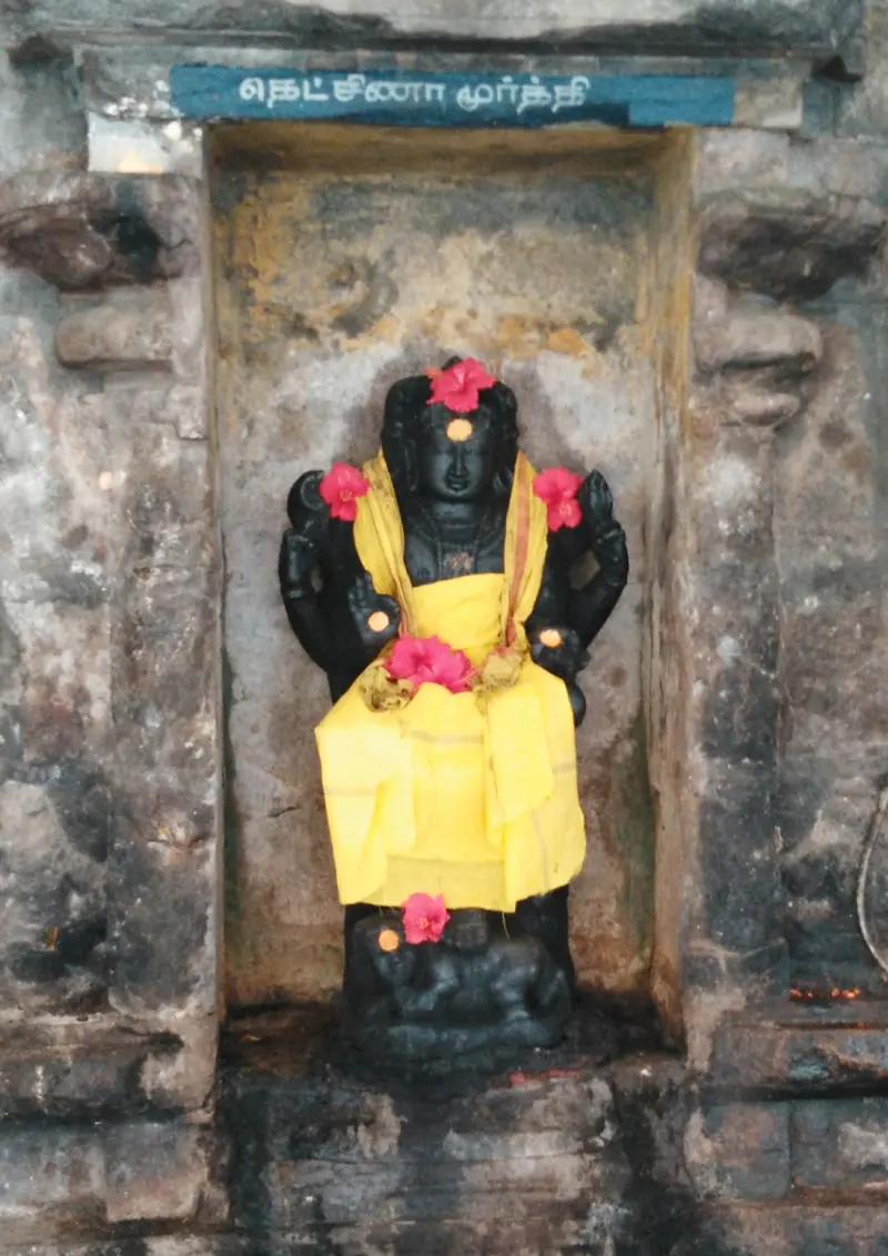 A four-armed god in yellow cloth seated on a bull