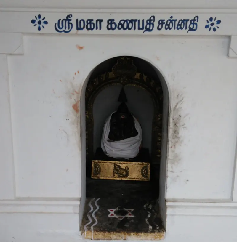 Small white niche shrine with a cloth-draped Vinayakar idol