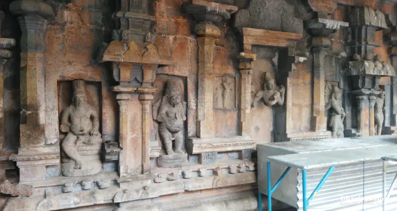 Carved stone figures in niches between pilasters on a weathered wall
