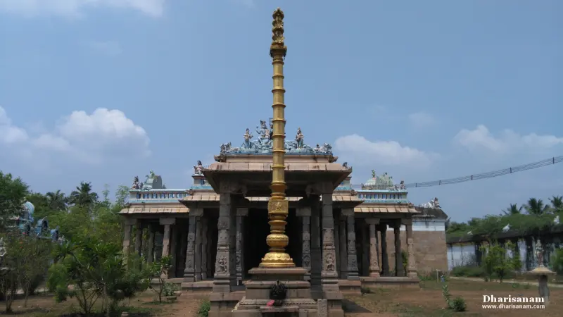 Tall gilded flag post in front of a pillared hall with sculpted roof edges