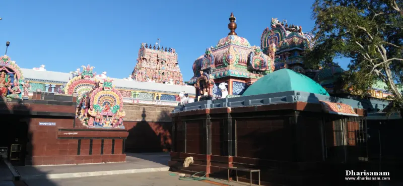 Several painted shrine roofs and a green dome, with a tower far behind, in sunlight.