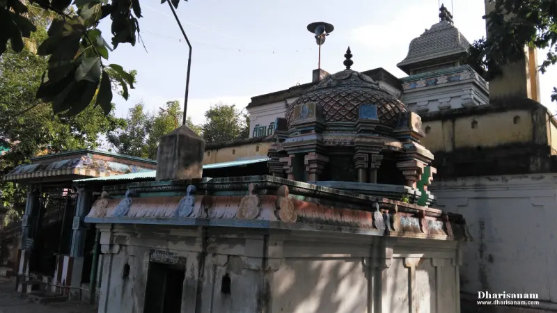 A shrine with a tiled dome and decorated cornice, a tower and whitewashed wall behind it