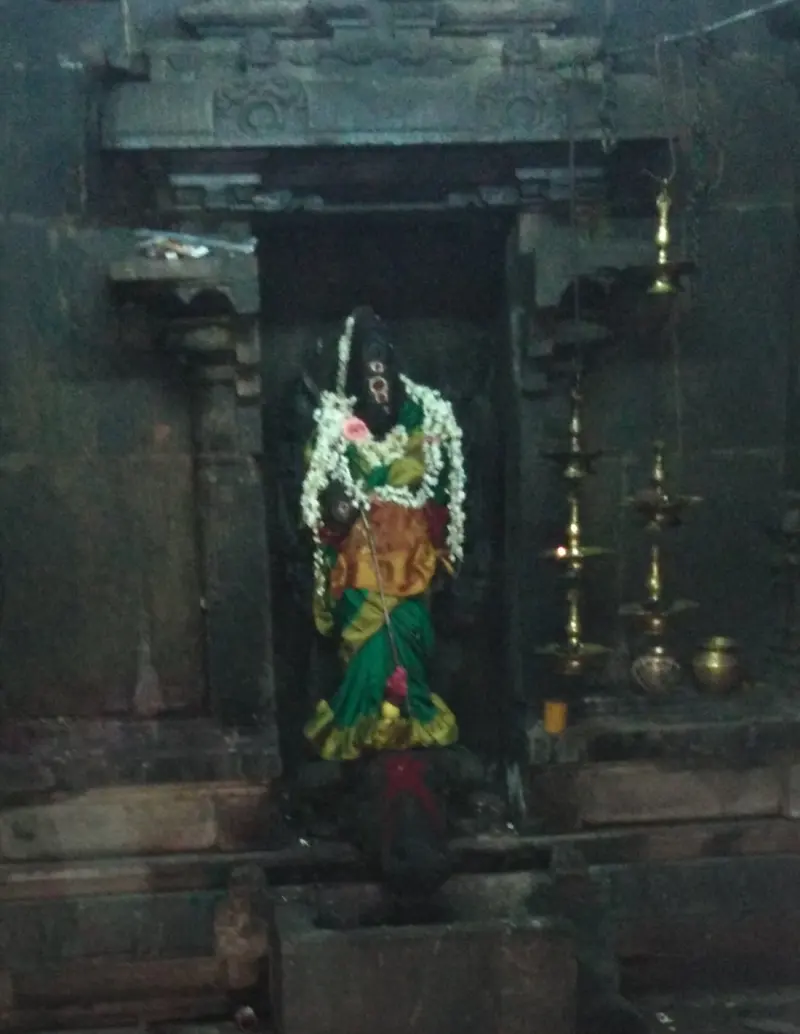A garlanded standing figure in a niche, with brass lamps