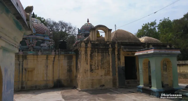 Weathered yellow corridor walls with domed roofs and a painted tower, and a small arched shrine in front