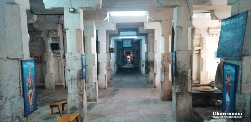A long stone hall with rows of pillars and framed pictures, with a lit sanctum at the far end
