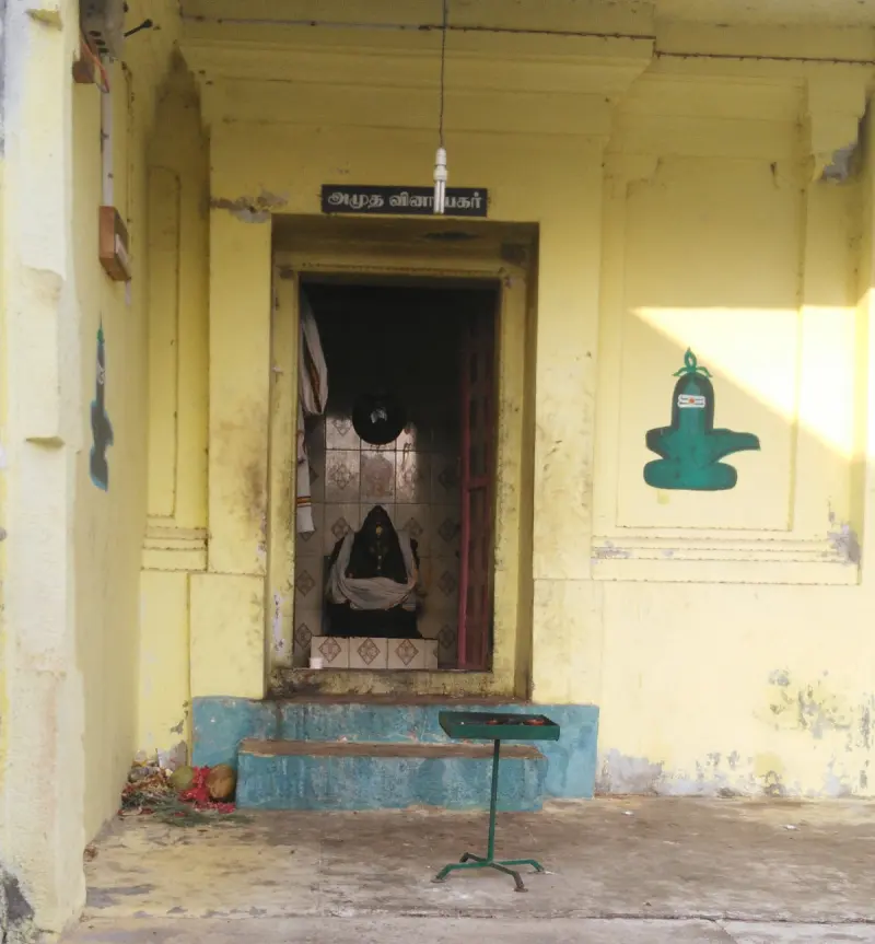 A yellow doorway with Amutha Vinayakar board, idol within