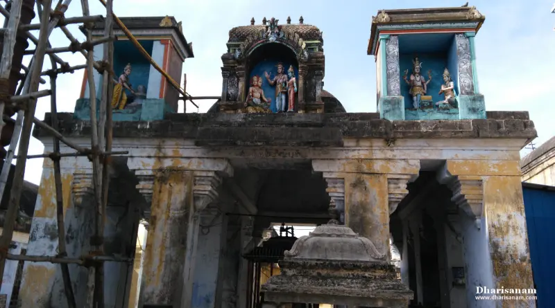 A weathered pillared gateway with painted figures in three niches above, under scaffolding