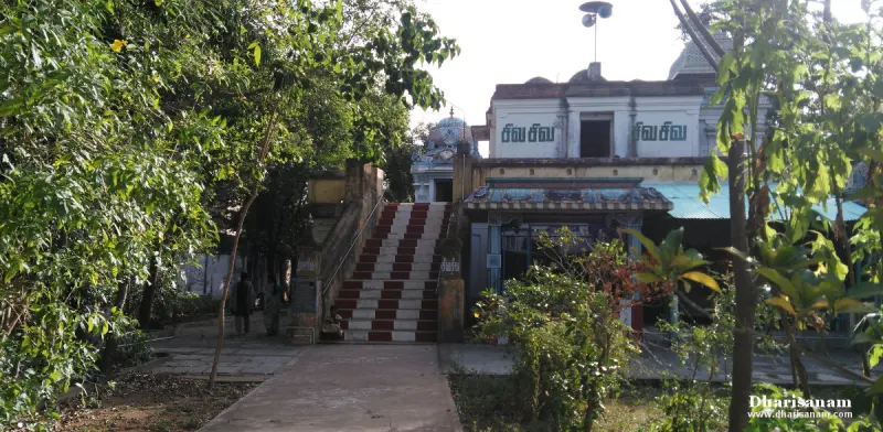A wide red-and-white painted stairway between trees leading up to the temple buildings