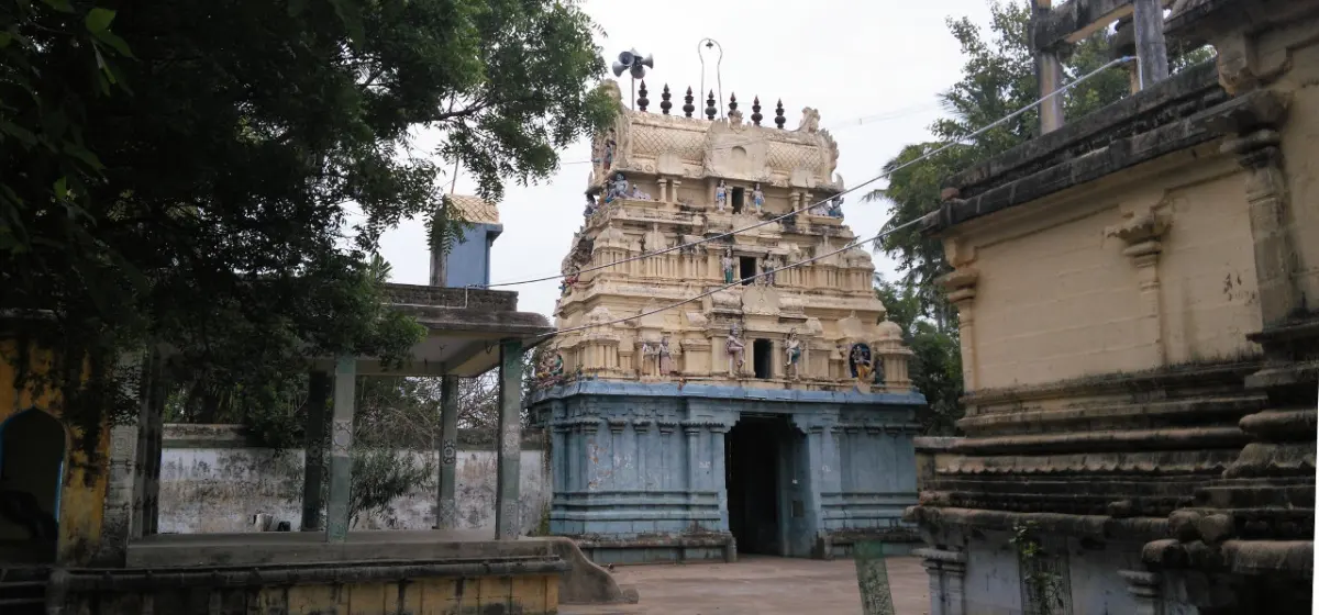 A three-tier tower with stucco figures above a blue-grey gateway, trees on both sides