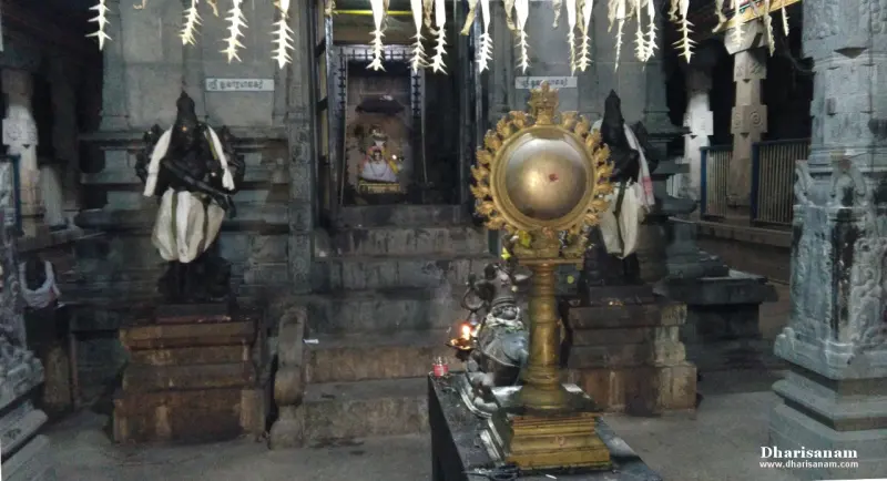 Steps leading to a doorway flanked by two black stone guardian idols, with a deity inside