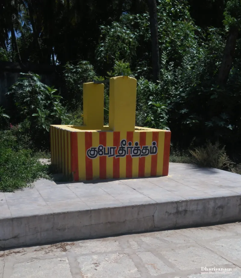 A small yellow and red striped well on a raised platform with its name painted in Tamil