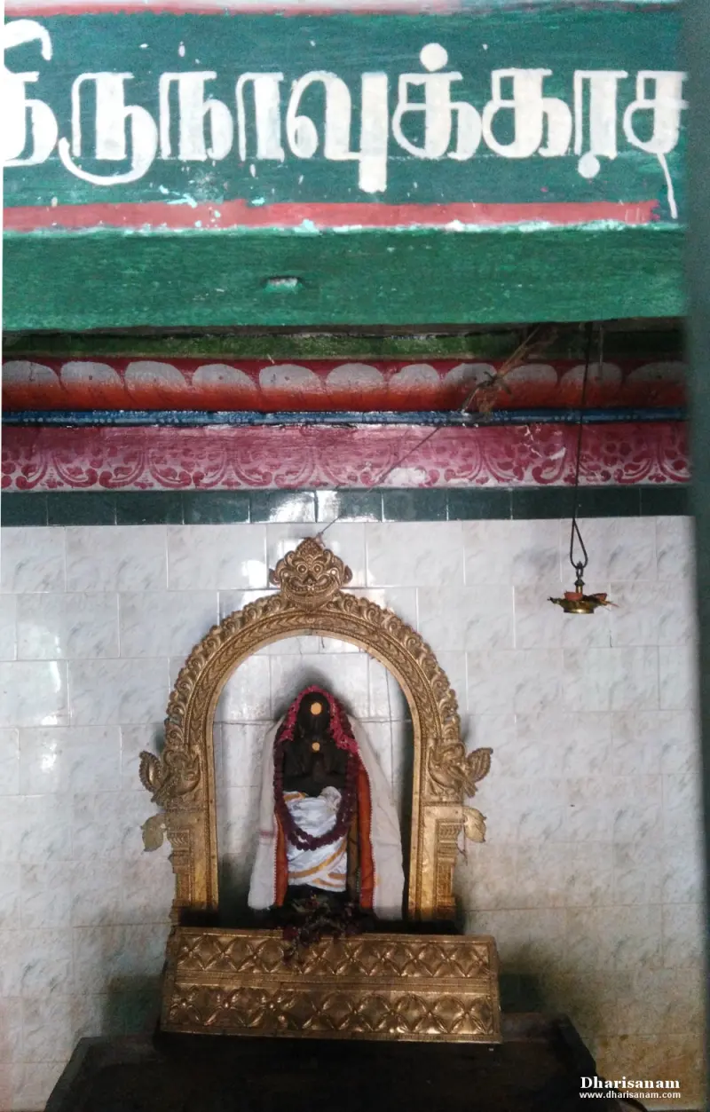 A small image with a garland in a gilded arch, below a green board painted with the saint's name in Tamil