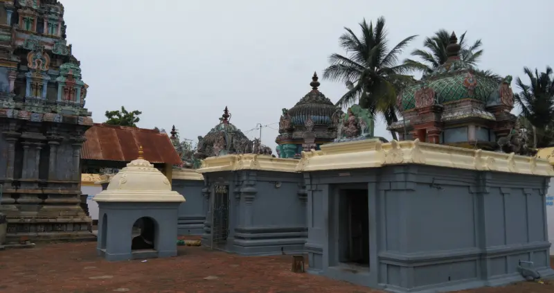 Grey shrines with domed roofs and the tall tower at left, around a brick-paved courtyard.
