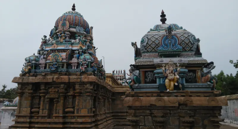 Two painted towers close together, the right one with a seated Vinayakar on its front