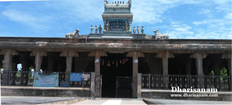 Pillared hall with two Nandi figures and small figures on its roof, under a blue sky