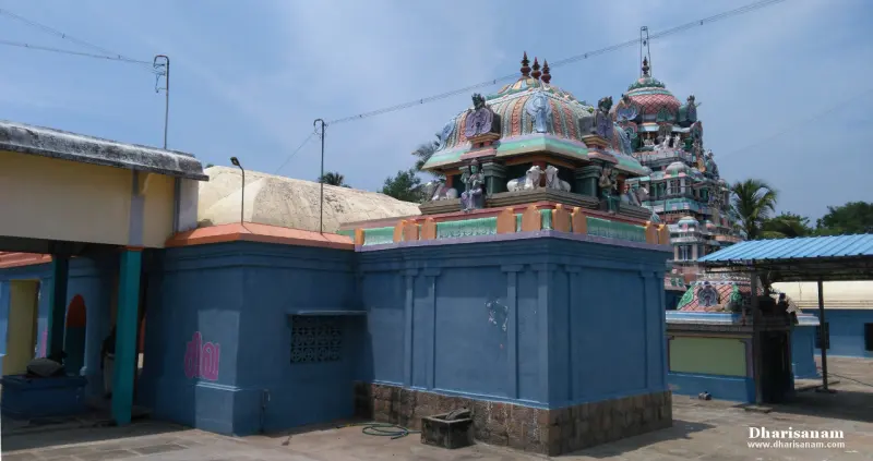A painted dome with sculpted figures on a blue-walled shrine, and a larger tower rising behind it.