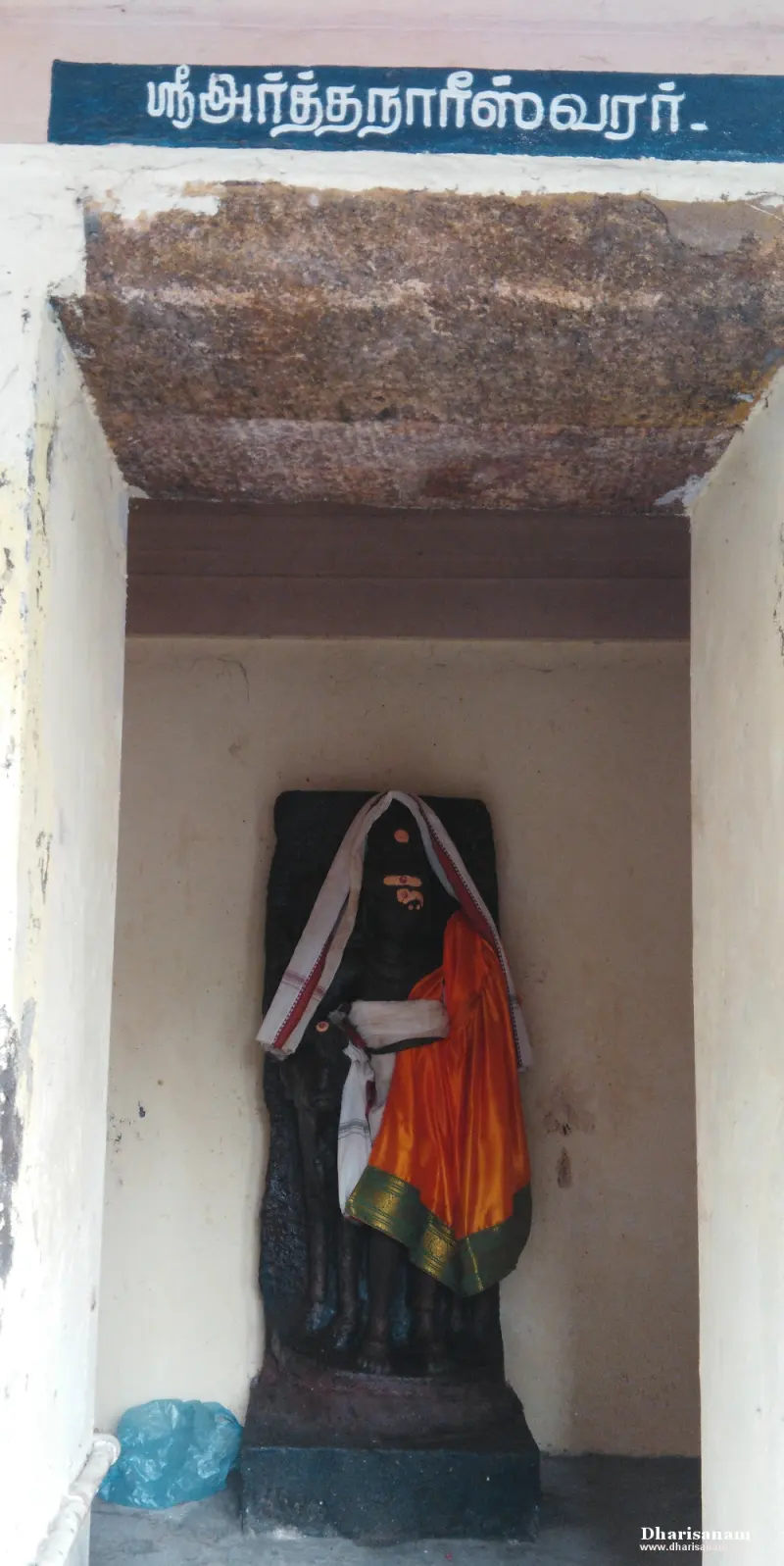 Half-Shiva half-Parvathy idol in orange silk under a name board