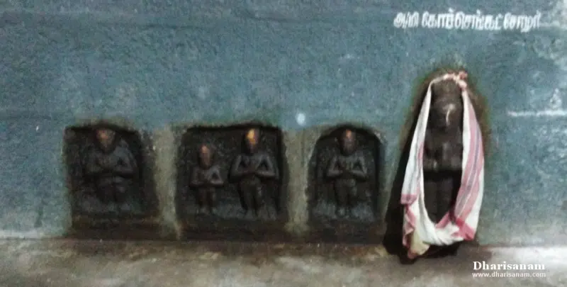 Three small figures with joined hands in wall recesses, and a taller idol in white and red cloth, below a Tamil label