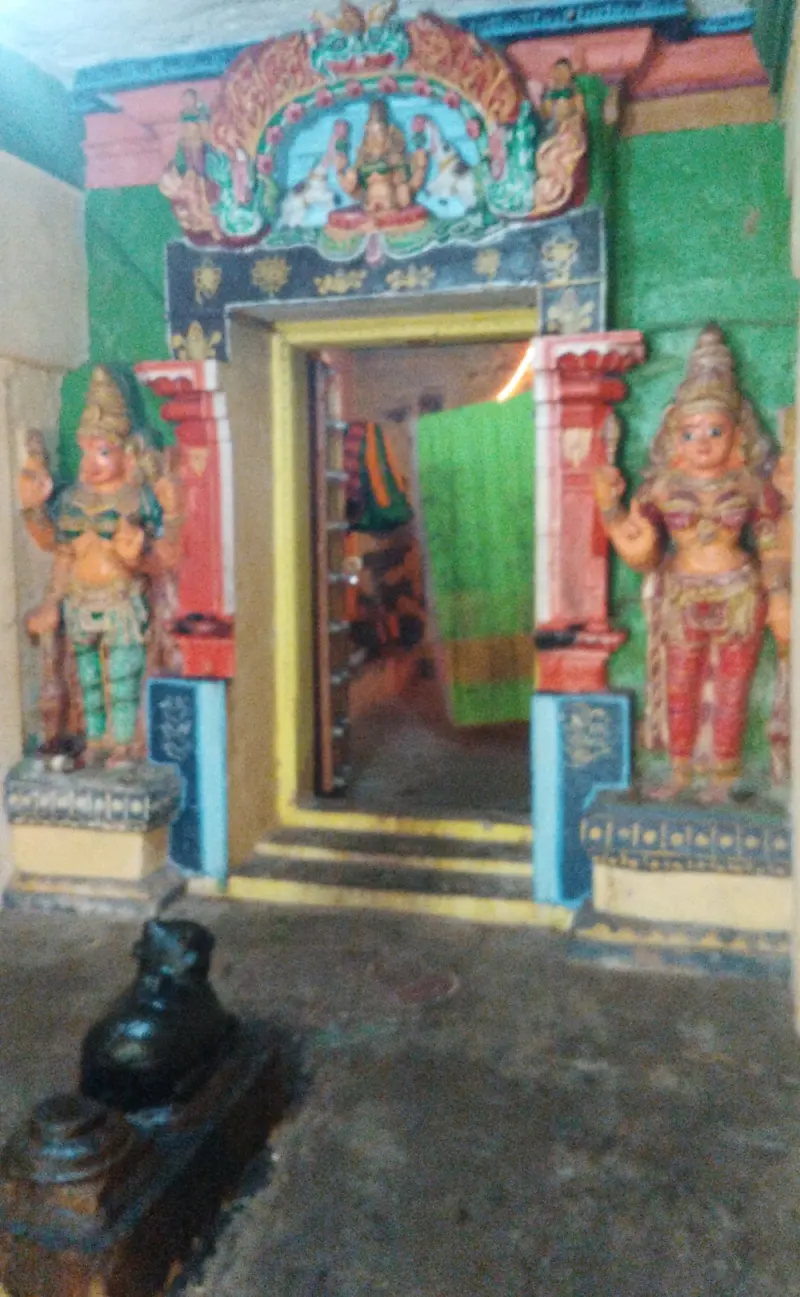 A colourful doorway flanked by two guardians, a Nandi before it