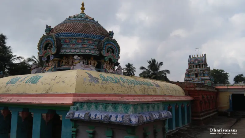 Domed vimana with painted figures above a shrine roof, and a tower in the distance