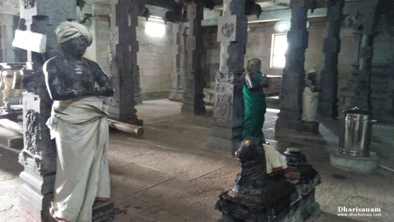 A statue of a man in a turban and white dhoti, another figure in a green sari, and a small Nandhi in front
