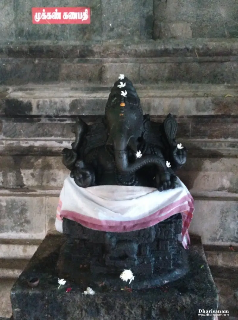 Dark stone Vinayakar idol with flowers and a Tamil name board above