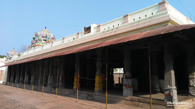 Long pillared corridor with a tin roof, and domed shrine tops behind it
