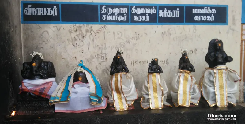 Six black stone idols in cloths, with Tamil name boards above them