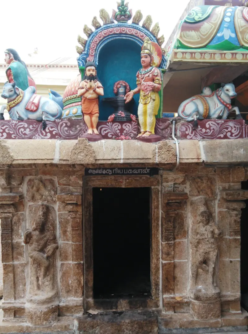 Stone shrine door with carved guardians and colourful statues above