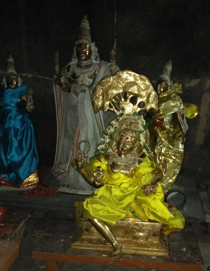 A seated golden goddess in yellow silk between standing bronzes