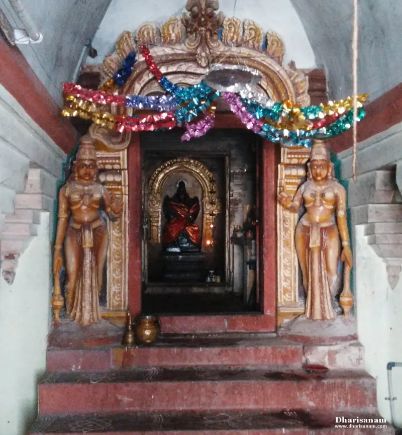 Steps lead to a shrine door decorated with paper garlands, with a painted guardian figure on each side of the doorway