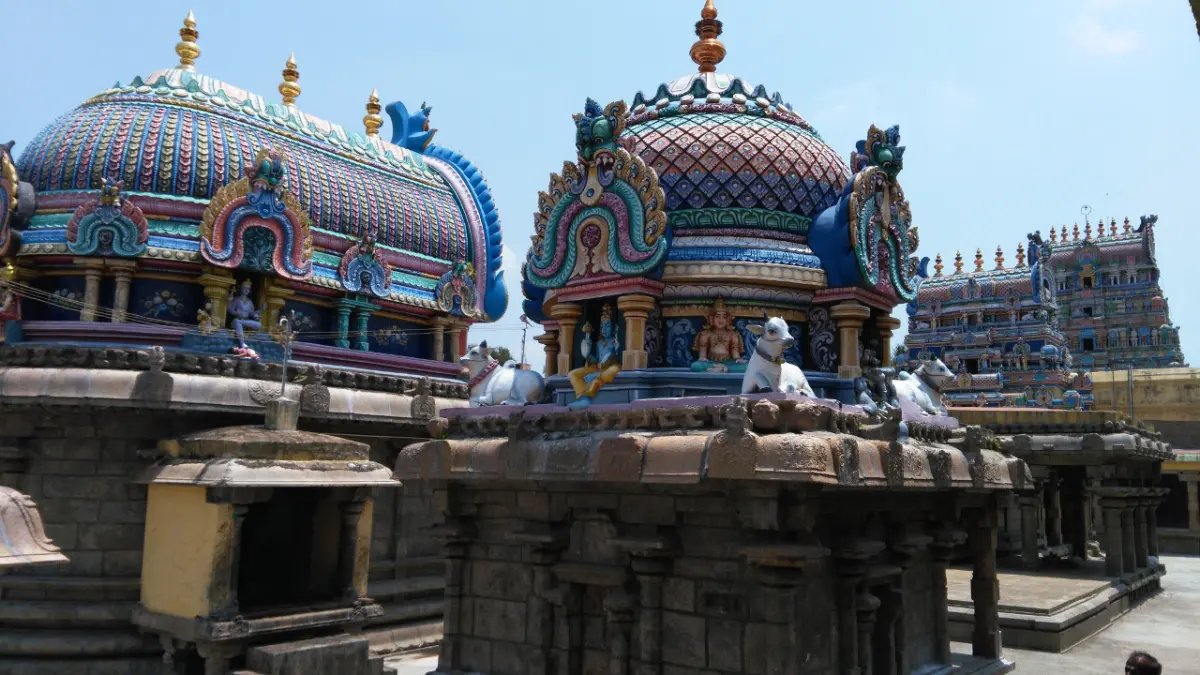 Brightly painted shrine domes with white bull statues, and a tiered tower rising in the background