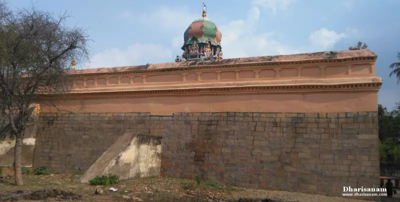 A long wall of stone blocks topped by a plastered band, with a small domed roof showing above it