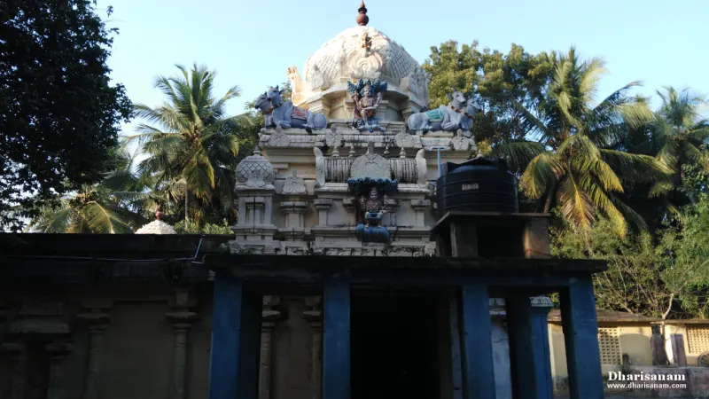A white tower with bulls and painted figures behind a dark pillared hall with blue pillars, palm trees beyond