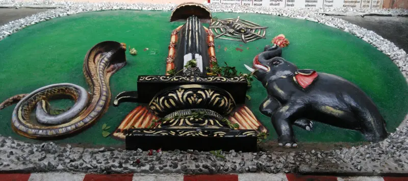 A painted relief showing a lingam on its base, a coiled snake on the left, a spider above and an elephant on the right.
